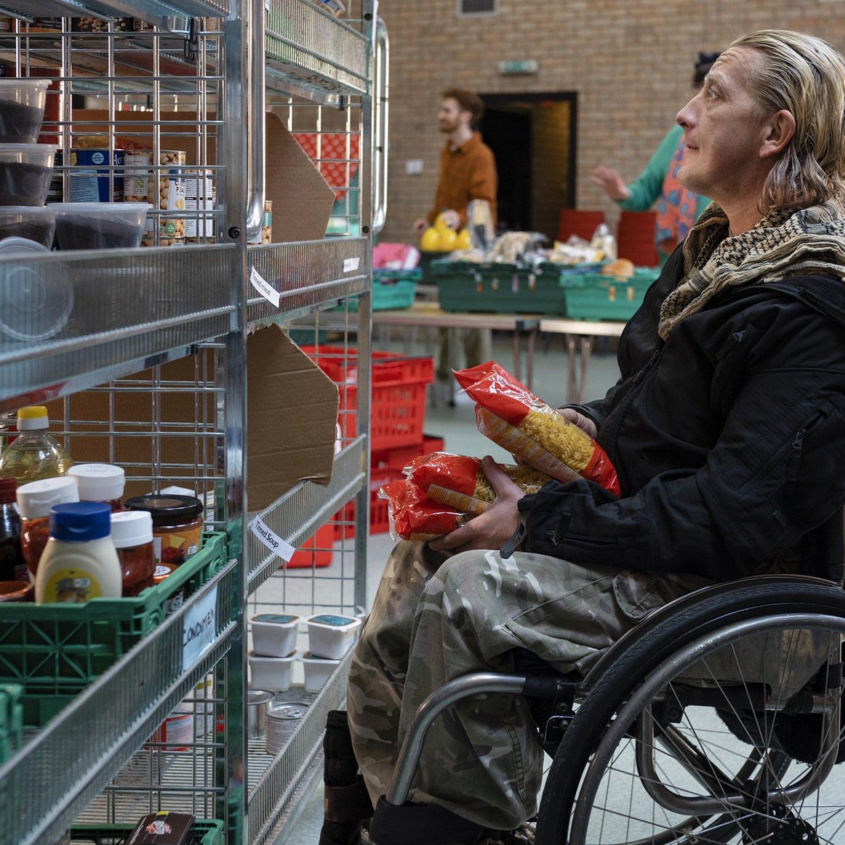 Ein Rollstuhlfahrer vor einem Regal mit Lebensmitteln