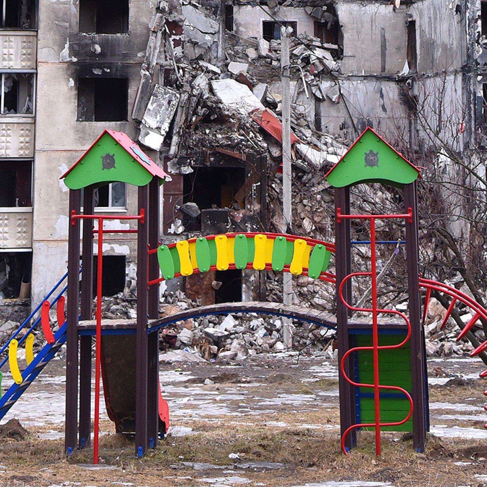 Zerstörtes Haus im ukrainischen Charkiw hinter einem Kinderspielplatz