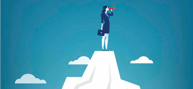 Eine Frau steht auf einem Berg und schaut in die Ferne, sie hat dabei die Hand über den Augen gehalten