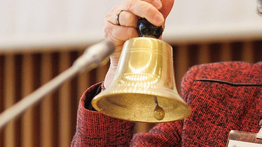 Synode der EKHN, Glocke Eine Hand hält eine Glocke