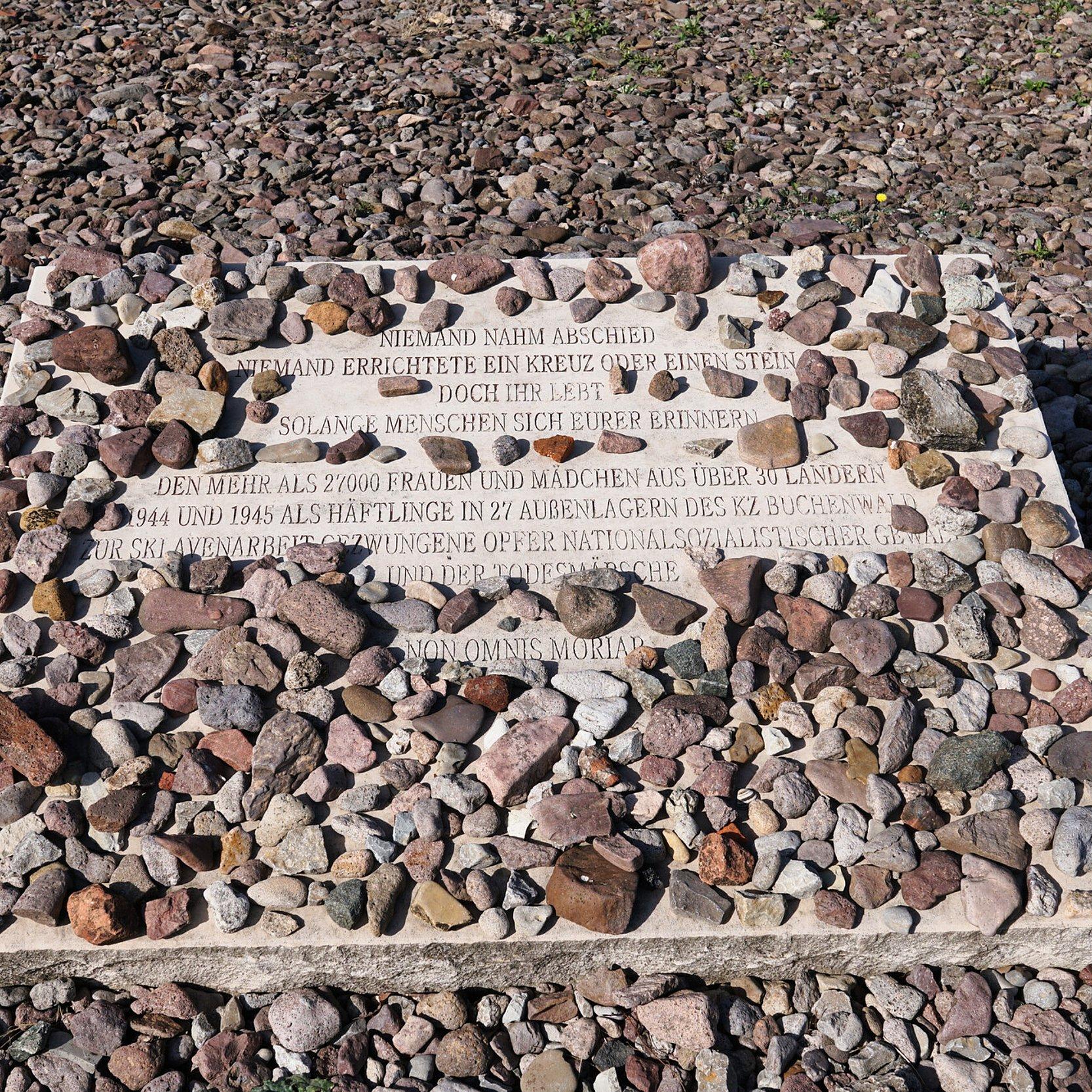 KZ Gedenkstätte Buchenwald. Eine Gedenkplatte mit Text liegt auf Kieselsteinen. 