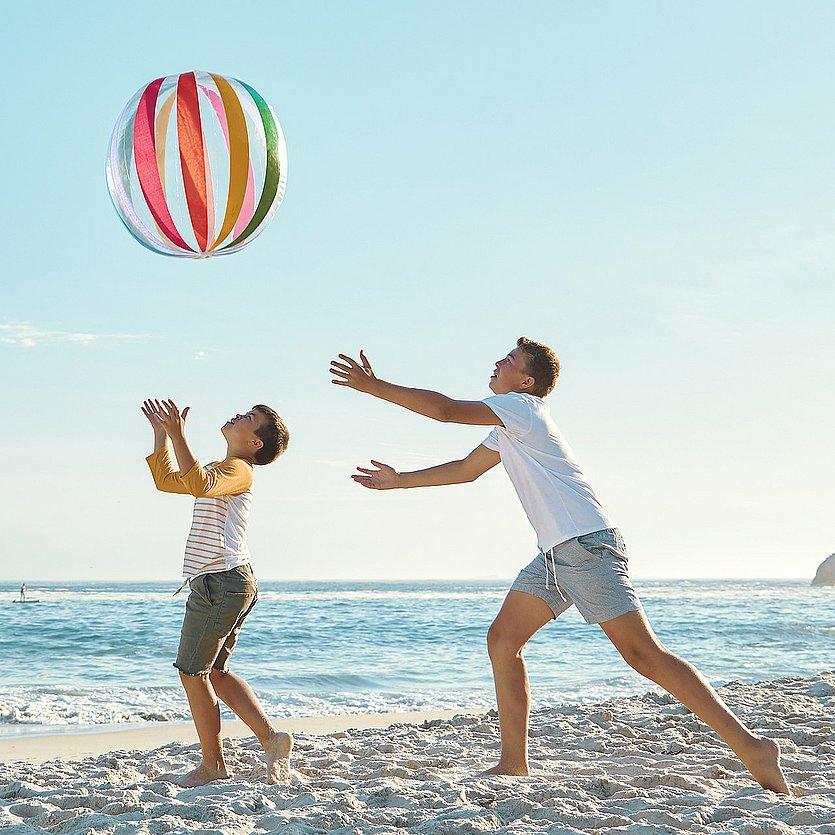 Zwei jungen spielen mit einem aufblasbaren Ball am Strand