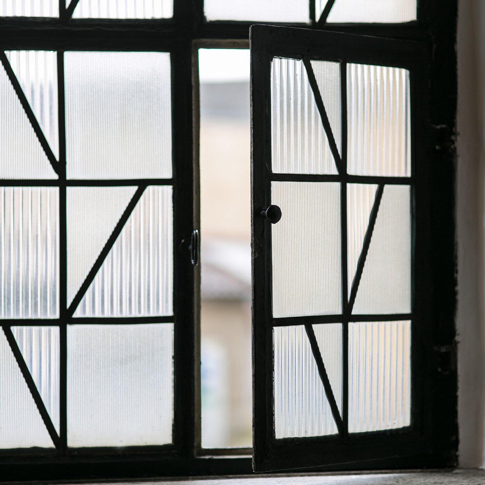 Fenserfront aus Reliefglas. Ein Teilfenster davon ist geöffnet