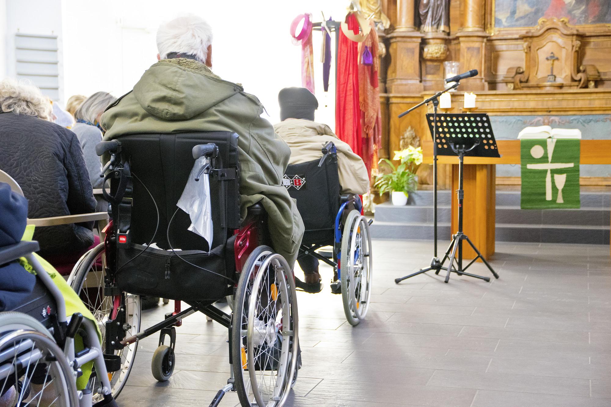 Rollstuhlfahrer*innen nehmen an einem Gottesdienst teil