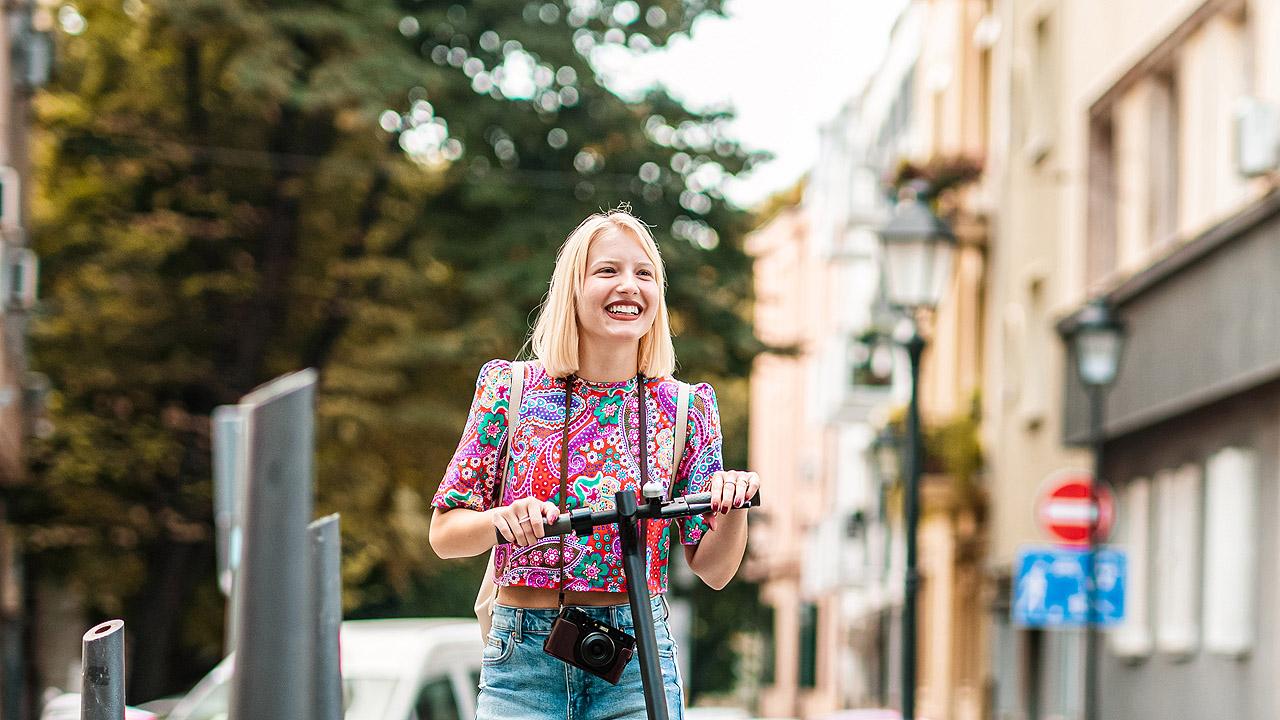 Eine Frau mit einem Roller erkundet die Stadt