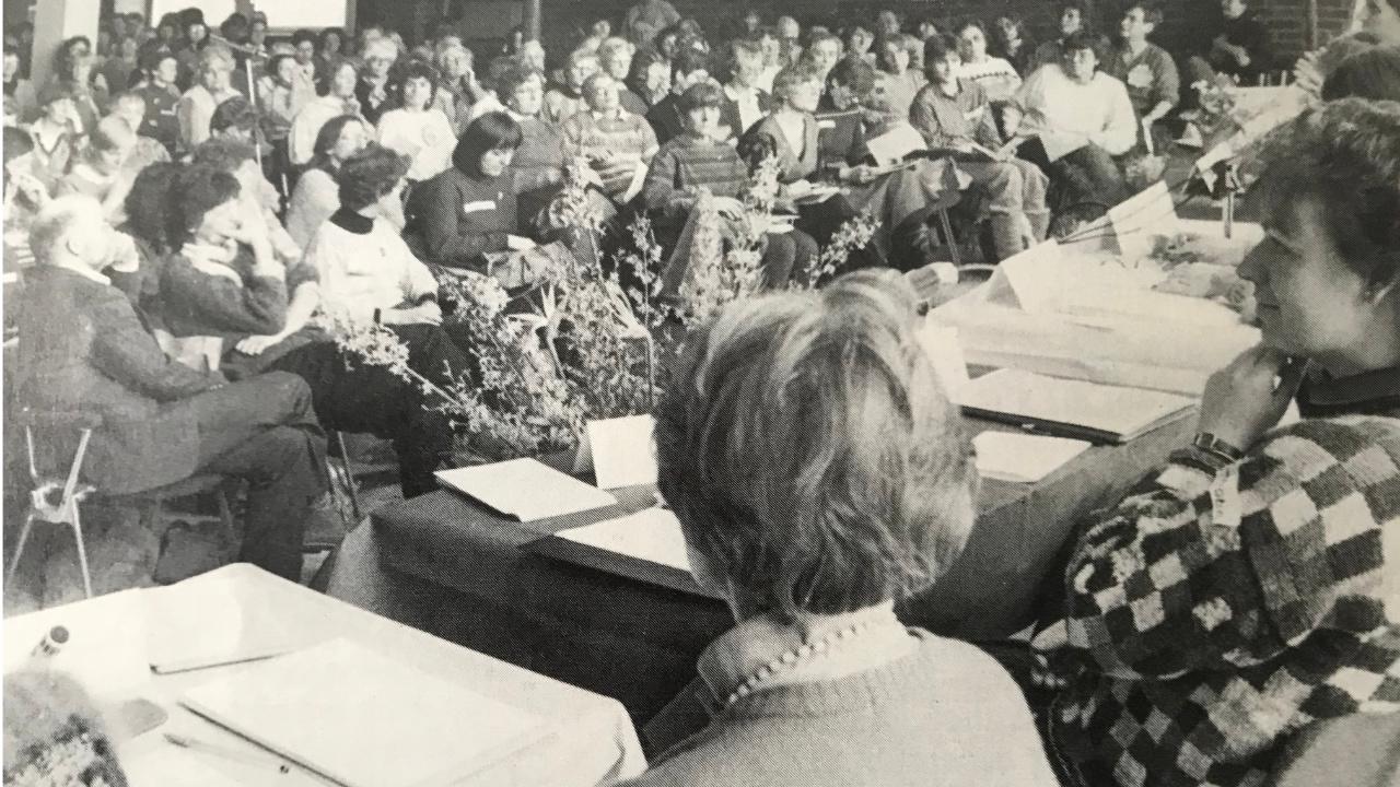 Über 400 Frauen sitzen in einem Saal in Darmstadt, mehrere Frauen sitzen auf dem Boden mit dem Rücken zur Kamera. Das Bild ist schwarz-weiß