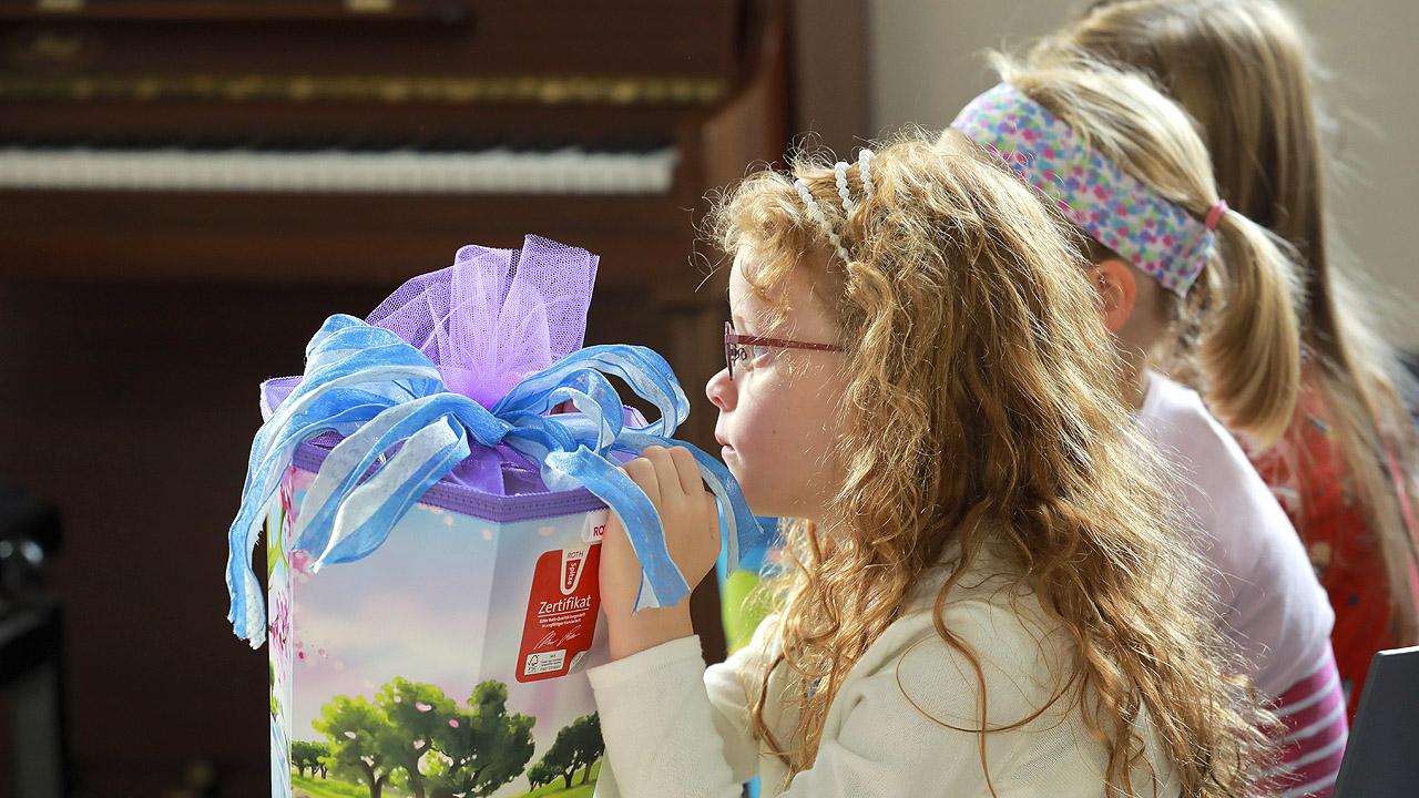 Ein Mädchen mit einer großen Schultüte sitzt auf einer Kirchenbank