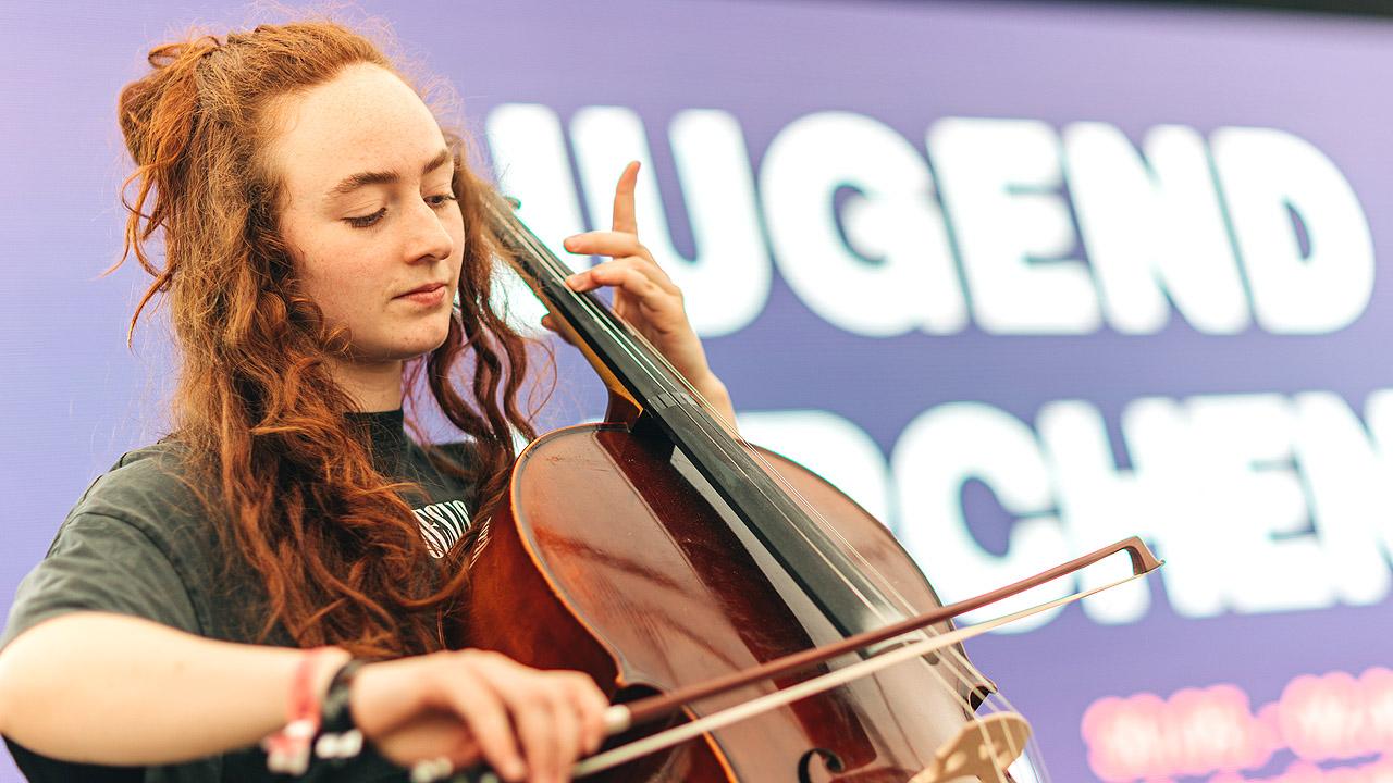 Eine junge Frau mit Dreadlocks spielt Cello