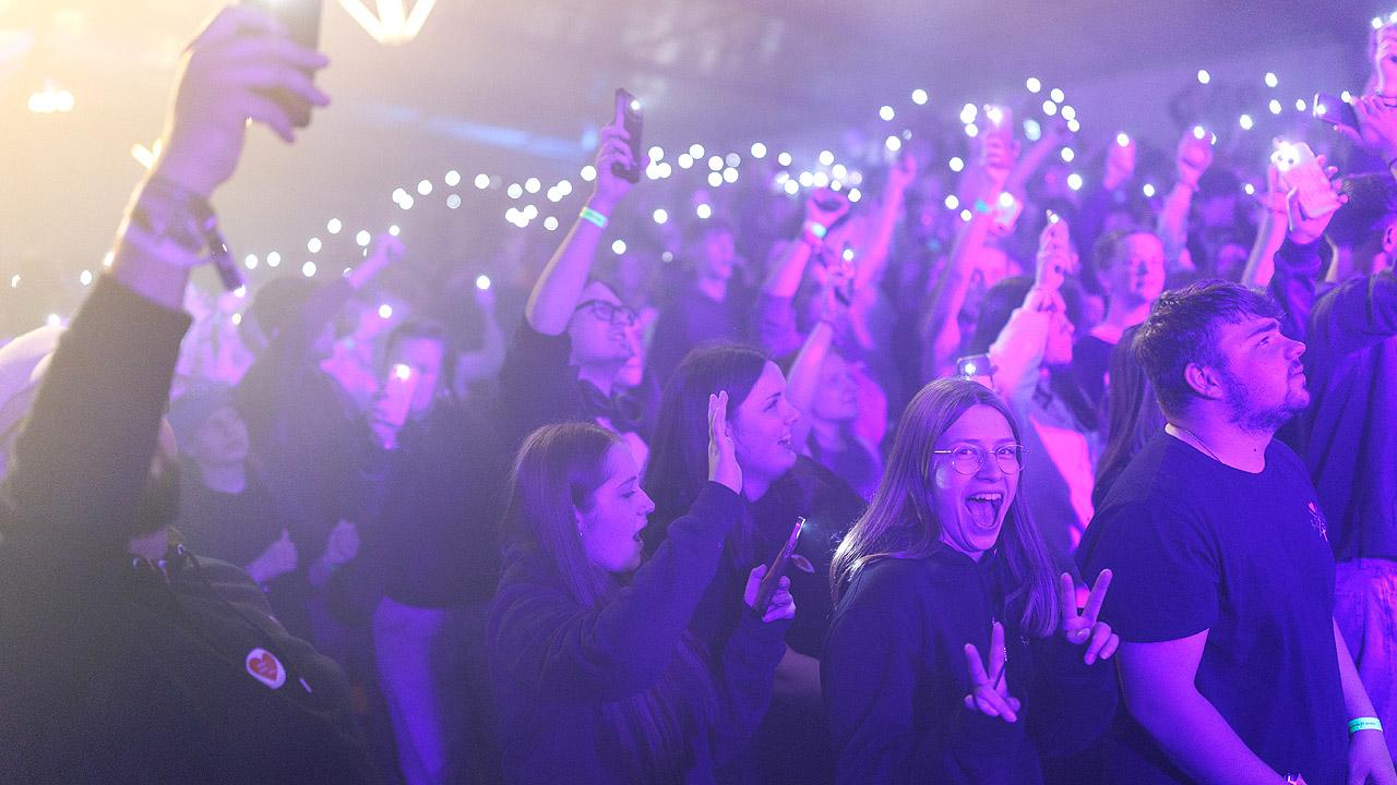 Jugendliche in violettes Licht getaucht, im Hintergrund Lichter, vorne eine gut gelaunte junge Frau