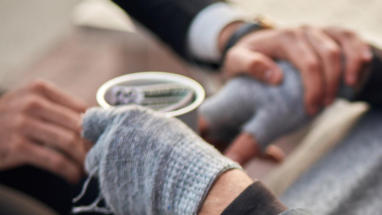 Jemand legt die Hand auf die Hand eines Obdachlosen