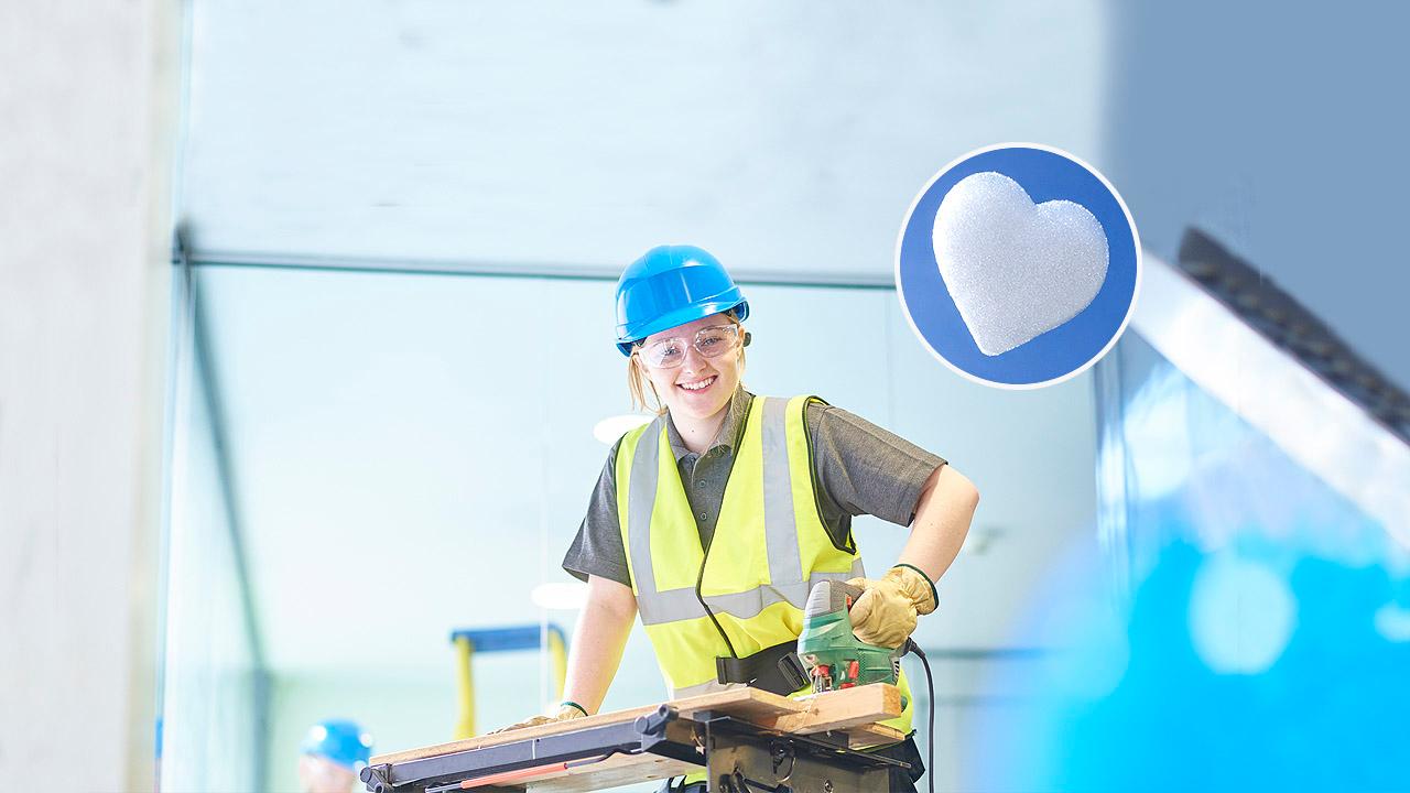 Eine junge Frau mit Helm in der Tischlerlehre