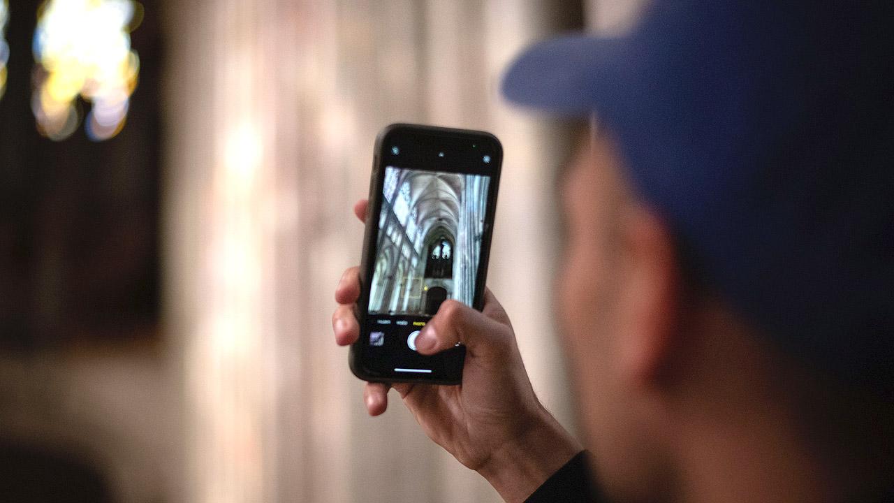 Ein Mann fotografiert mit seinem Smartphone den Innenraum einer Kirche