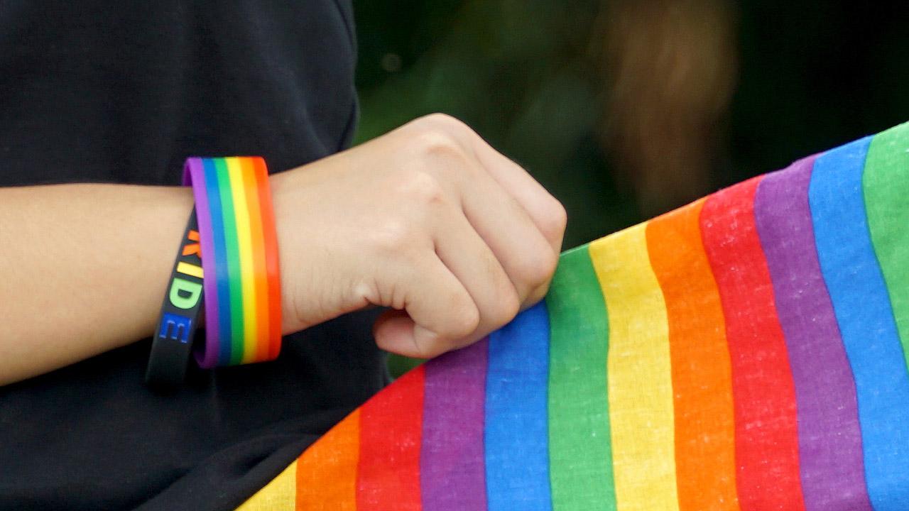 Hände halten ein Tuch mit Regenbogen-Steifen
