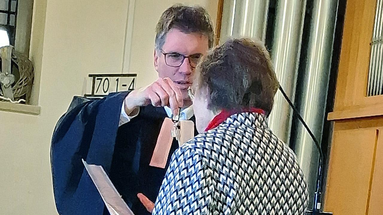 Ein evangelischer Pfarrer übergibt einen Schlüsselbund an eine ältere Dame