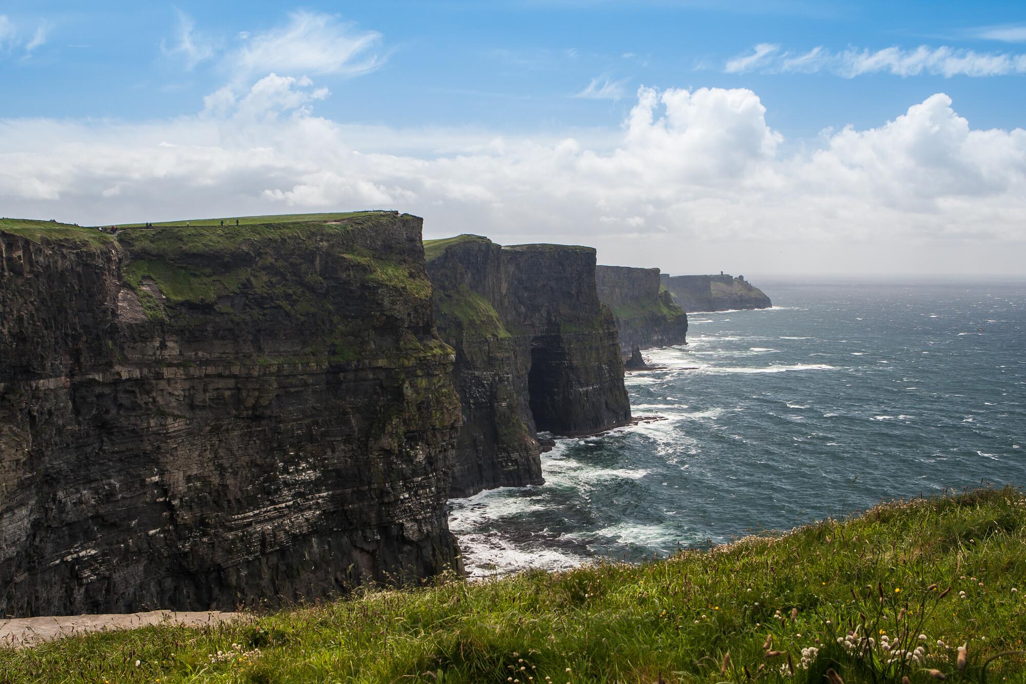 Im Sonnenlicht mit Meeresgicht ragen die steilen Cliffs of Moher aus dem Meereswasser in Irland.