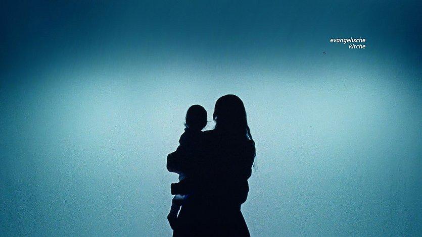 Weihnachtsfilm Silhouette einer Mutter mit Kind vor türkisfarbenem Lichtschein