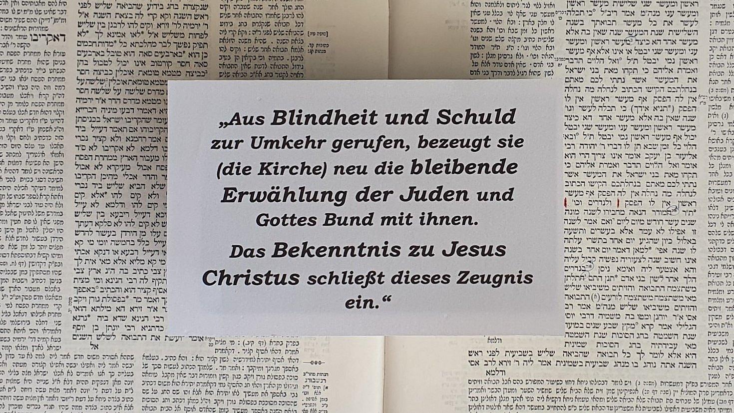 Zu sehen ist der Abschnitt aus dem Grundartikel der EKHN. Im Hintergrund eine Seite aus dem Babylonischen Talmud.