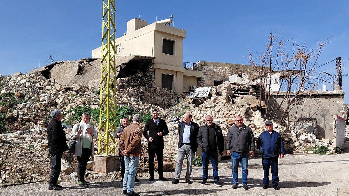 Zerstörte Kirche, davor eine Gruppe von Personen.