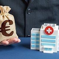 Spenden Krankenhaus Modell eines Krankenhauses und Mann mit kleinem Geldsack, auf dem ein Euro-Zeichen ist