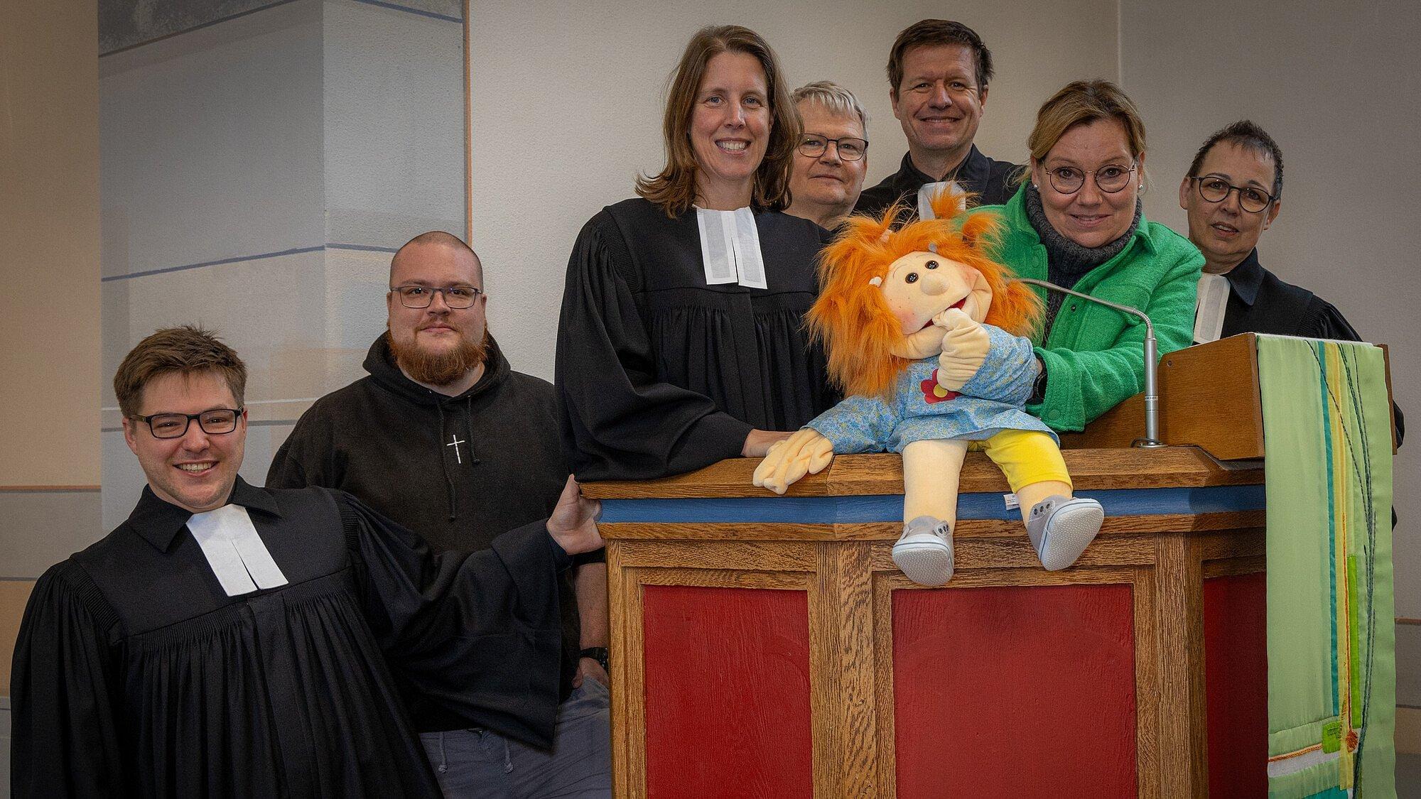 Sieben Personen mit Speilpuppe an der Kanzel