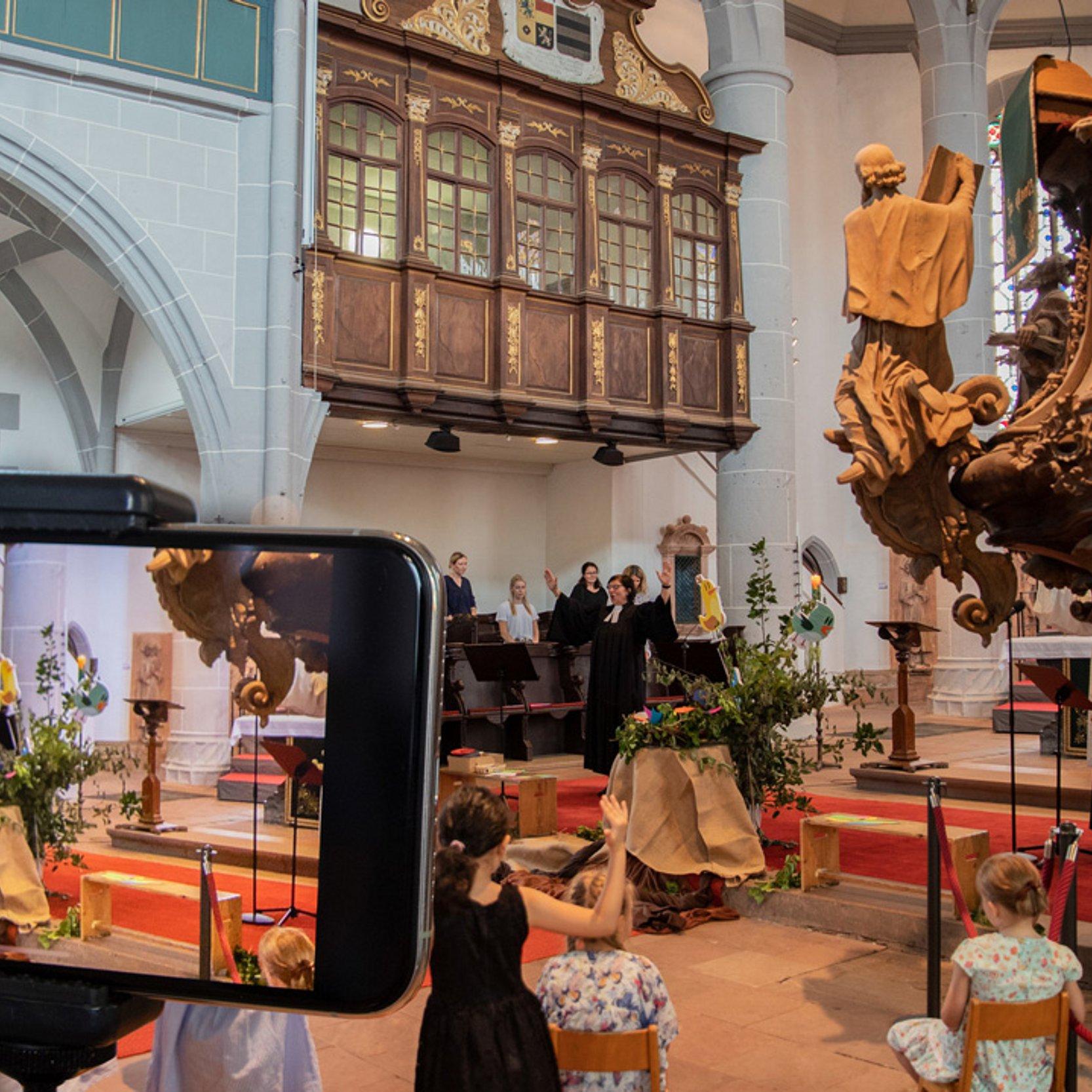 Einschulung Kircheninneres, Kinder, ein Bildschirm im Vordergrund