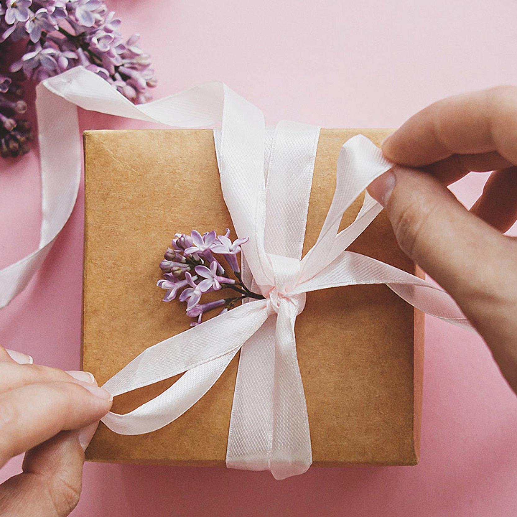 Geschenk Hände binden eine Schleife um ein Geschenk