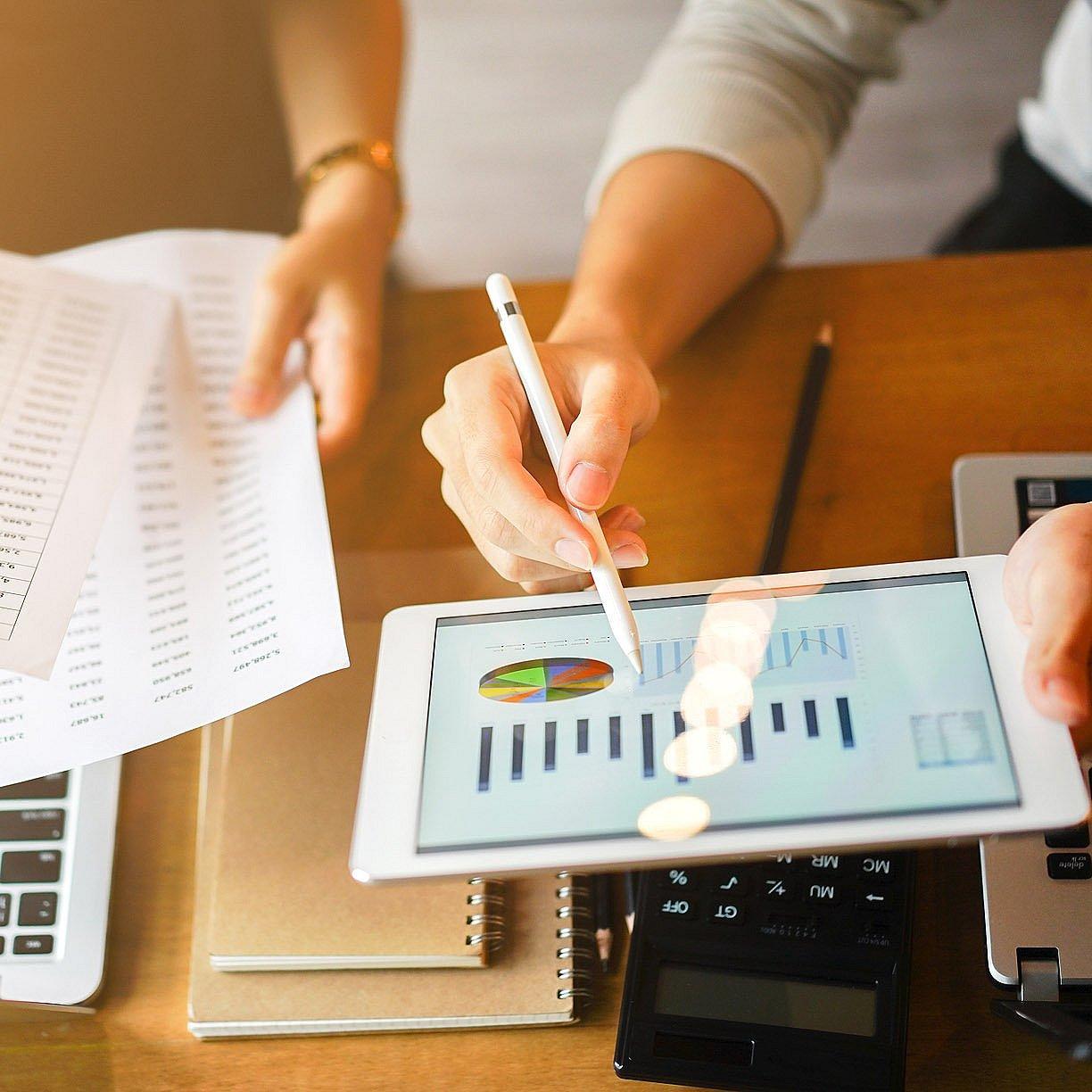 Zahlen und Statistiken Tablet mit Diagrammen und Blätter aus Papier mit Zahlenkolonnen