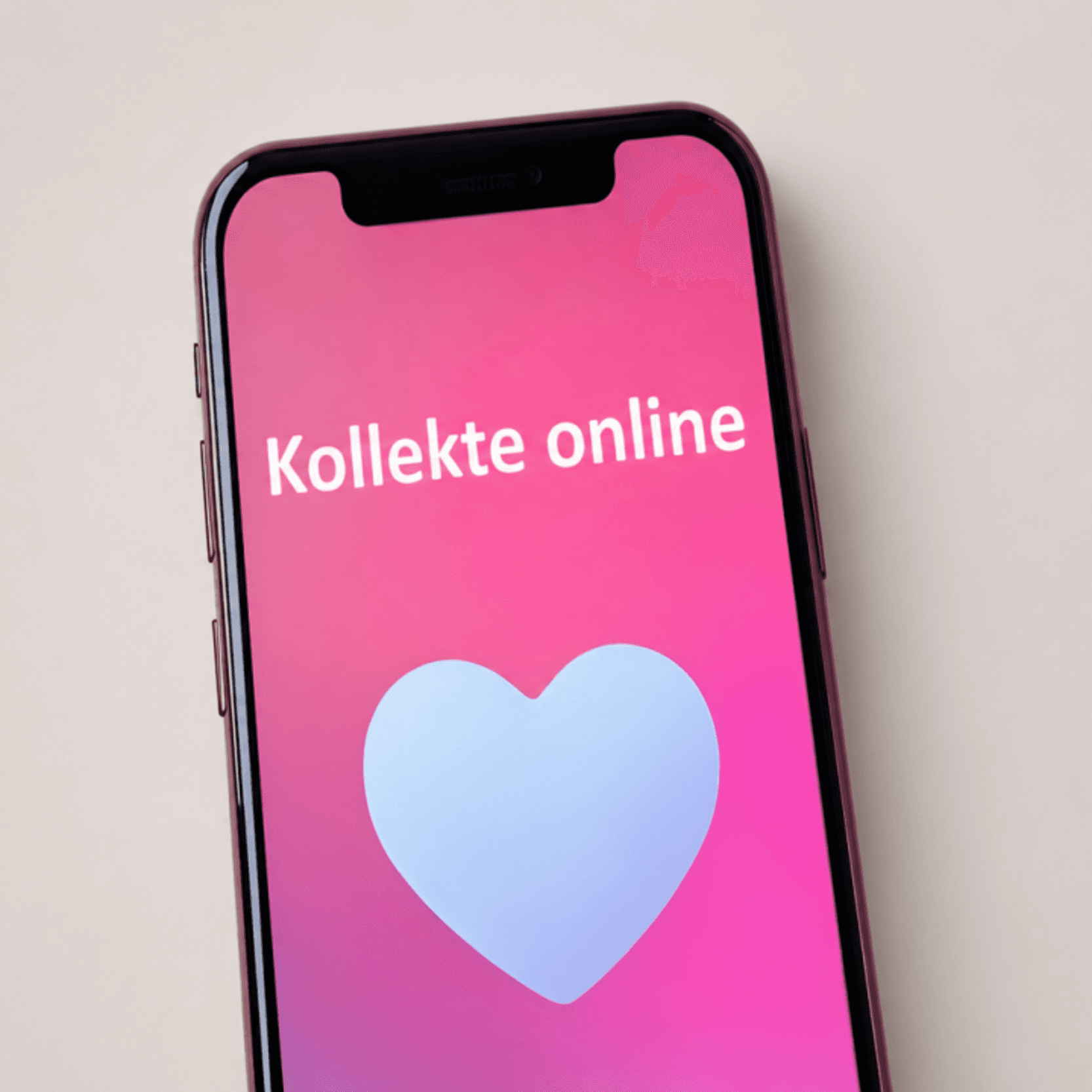 Kollekte online Ein Smartphone mit pinkem Bildschirm und der Aufschrift „Kollekte online“ sowie einem Herzsymbol steht vor einem neutralen, hellen Hintergrund.