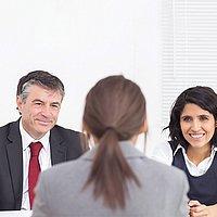 Bewerbungsgespräch Eine Bewerberin sitzt vor zwei Menschen, die das Bewerbungsgespräch führen