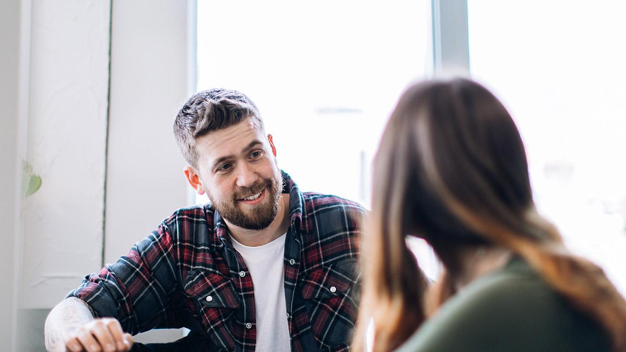 Ein jüngerer Mann (Sozialarbeiter) berät eine Schülerin