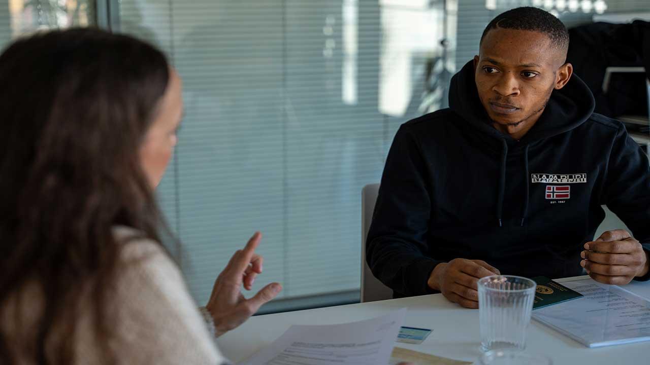 Gespräch über Formalitäten zum Kirchenasyl Gesprächssituation: Eine Frau berät einen Geflüchteten