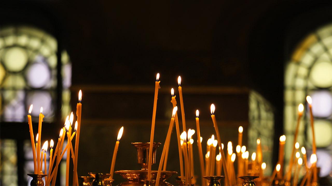 Brennende, lange, gelbe Kerzen in einer Kirche