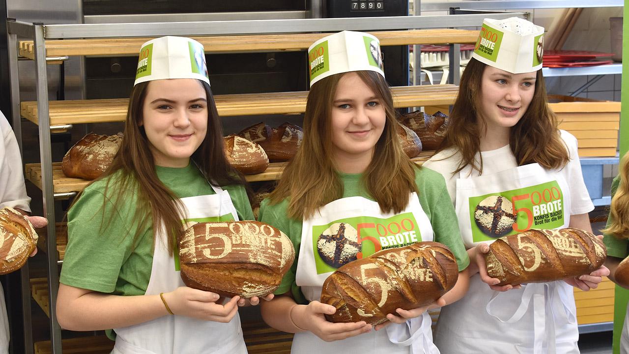 5000 Brote Mädchen halten Brote in den Händen