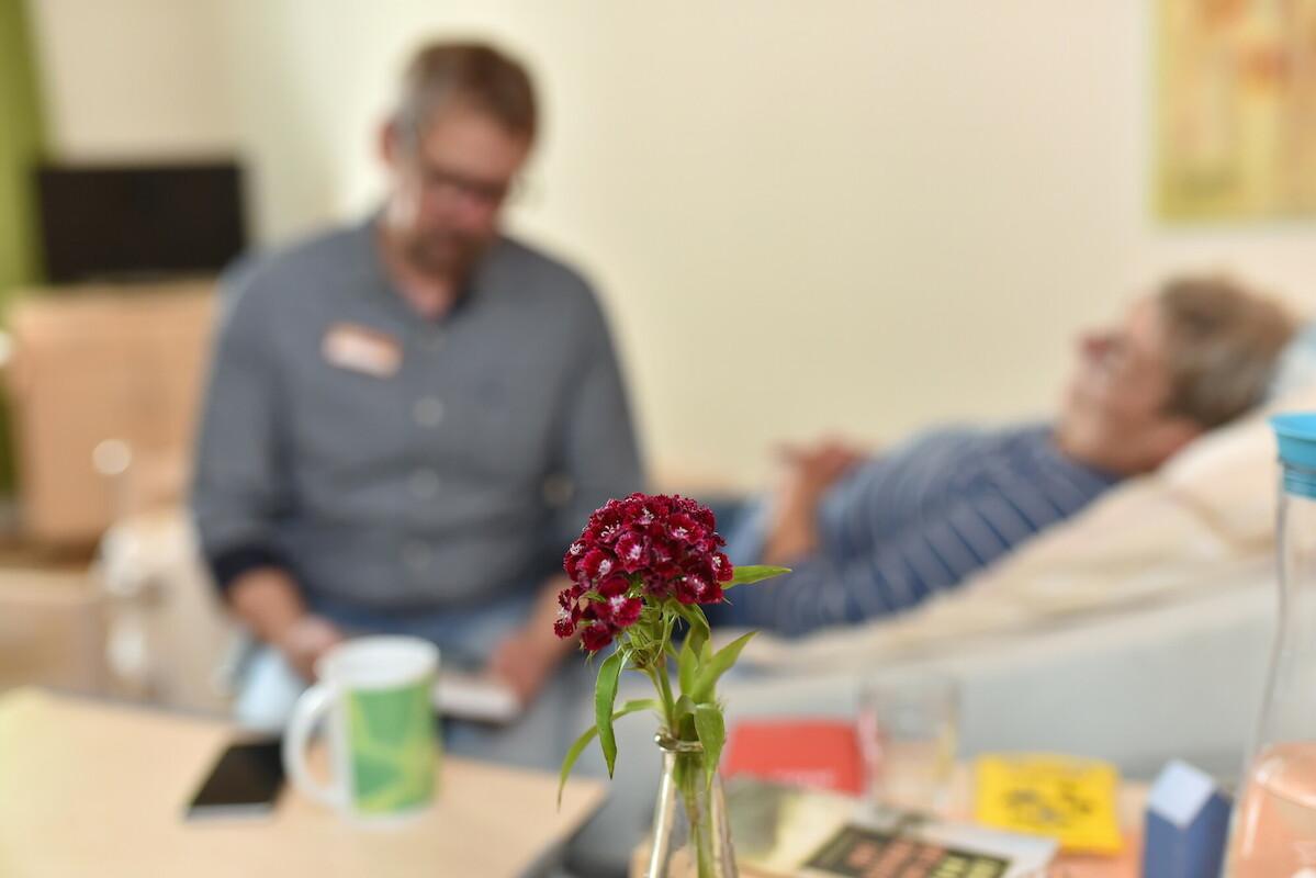 Am Pflegebett Jemand sitzt an einem Pflegebett mit Patient