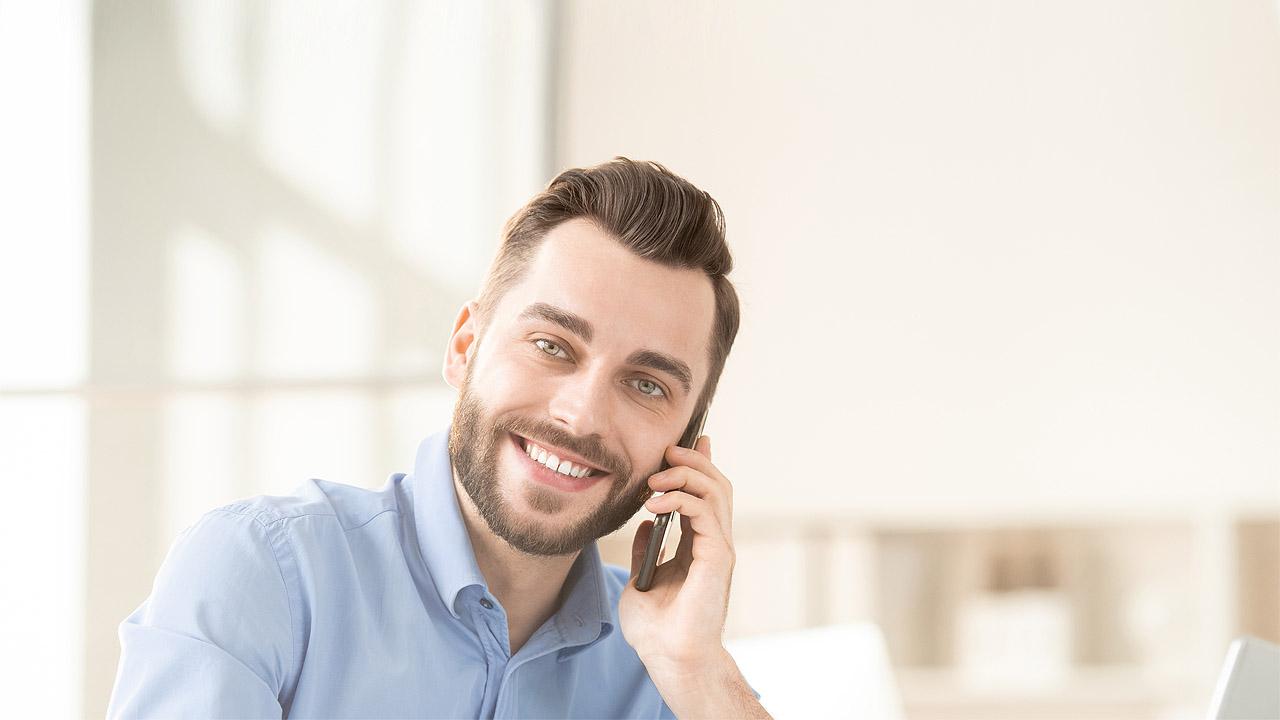 Ein Mann in hellblauem Hemd telefoniert