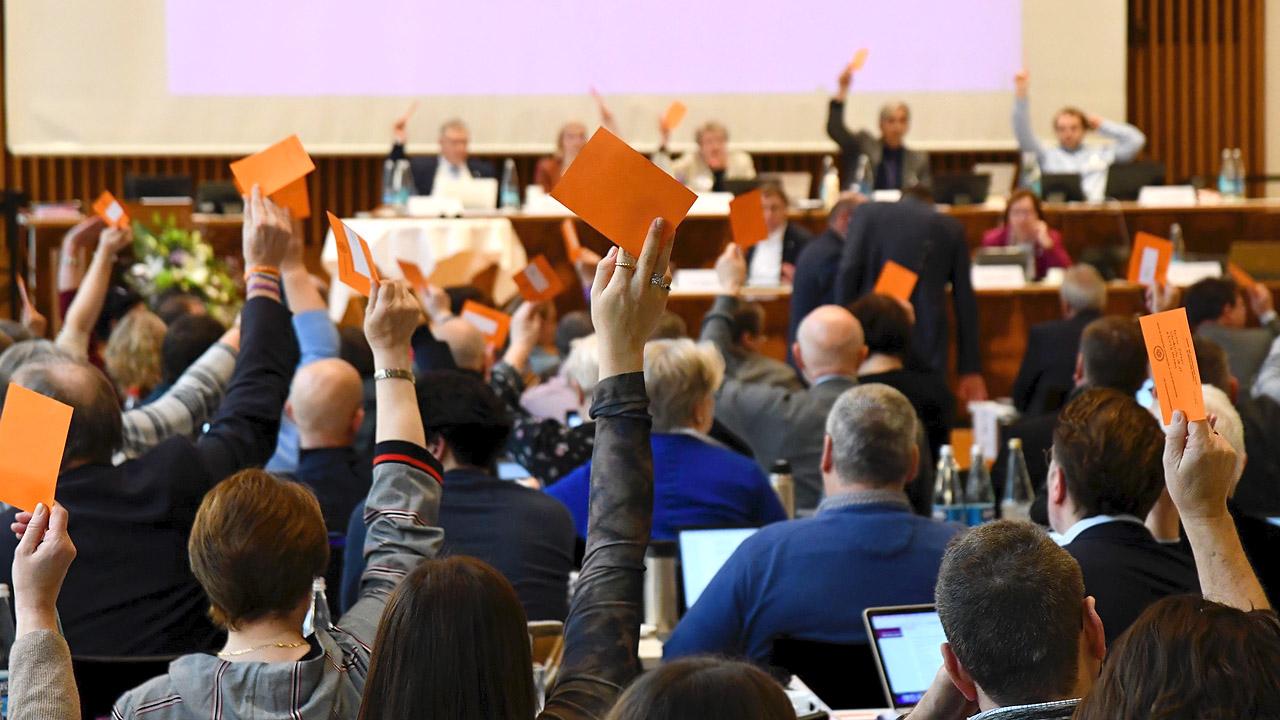 Synodale heben einen orangenen Zettel hoch