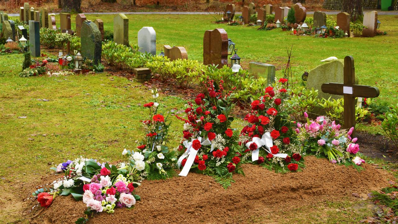 Frisches Grab Grab mit zu einem kleinen Hügel mit aufgehäufelter Erde, über der Blumen liegen