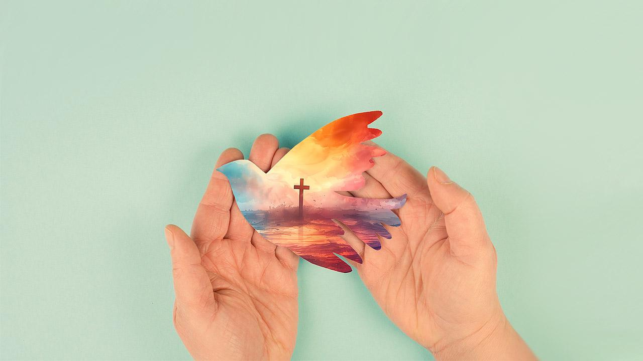 Papiertaube mit Kreuz in Händen