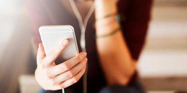 Hand einer jungen Frau, die ein Smartphone hält