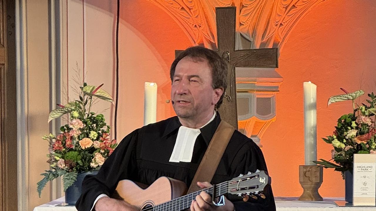 Bittlinger mit Gitarre vor dem Altar