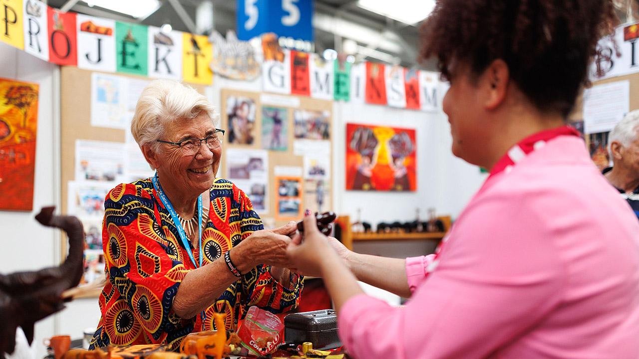 Begegnung Zwei Frauen an einem Stand reichen sich die Hände